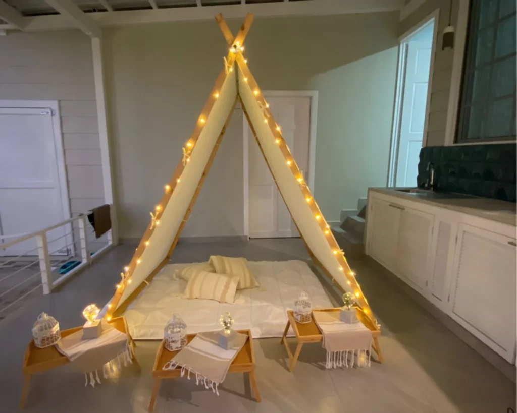 Ambientación para evento en terraza con carpa tipi y guirnaldas de luz, estilo acogedor.