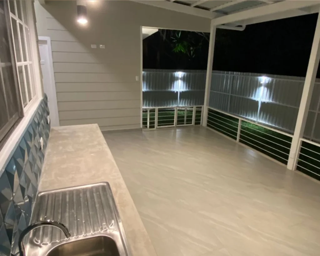 Barra de servicio exterior con fregadero de acero y sobre de concreto; vista hacia la terraza.