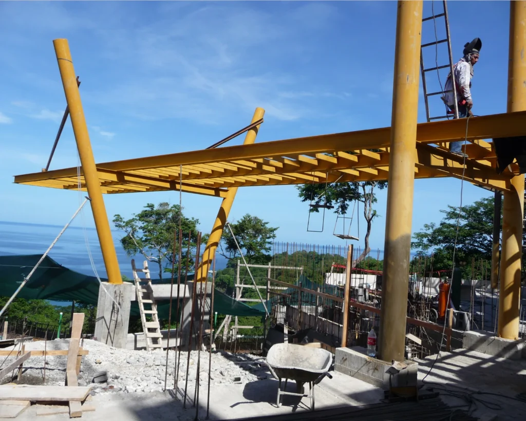 Montaje de estructura metálica del puente suspendido con vista al mar durante la obra.