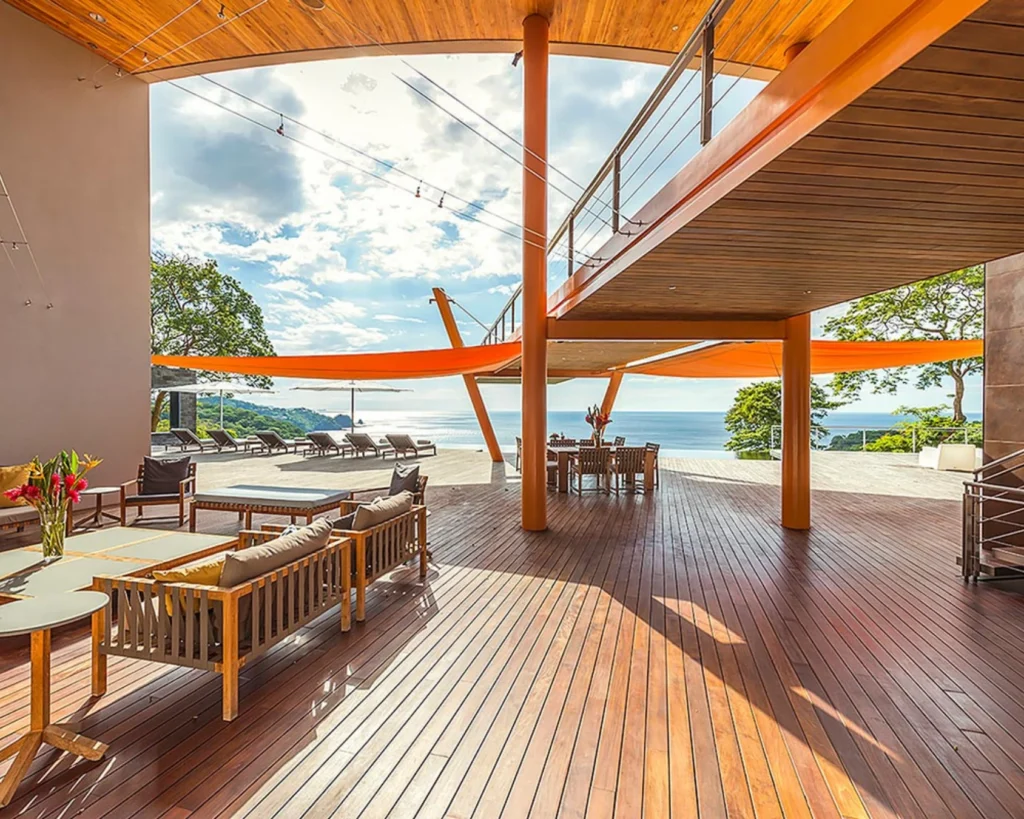 Terraza social cubierta con mobiliario exterior y vista panorámica al océano en residencia de lujo.