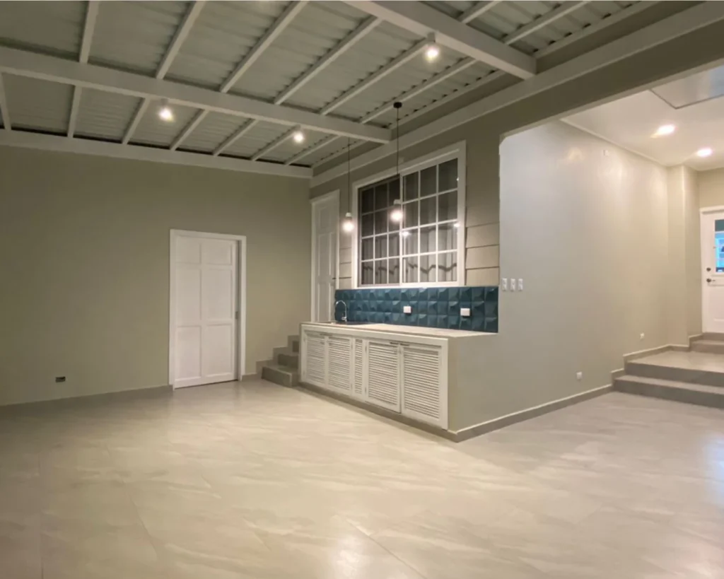 Terraza amplia y techada con mueble de servicio y enchape 3D azul, lista para reuniones.